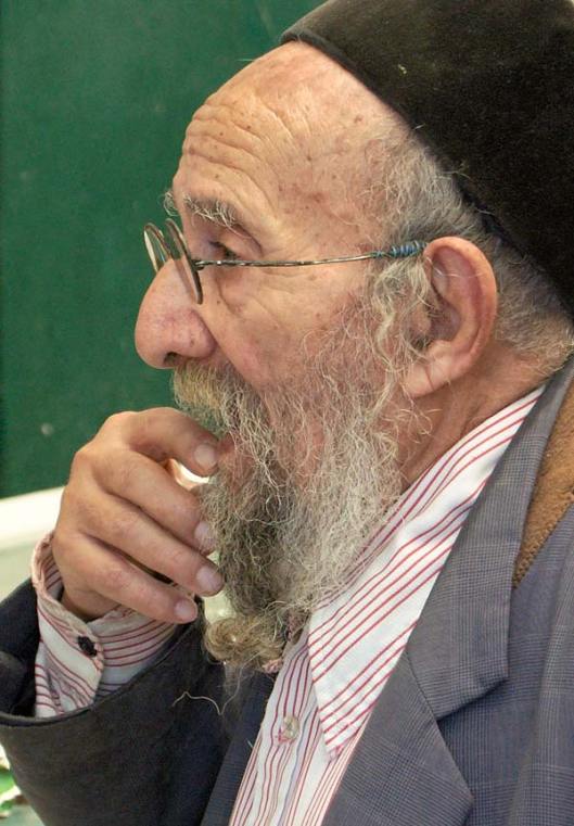 man standing with fingers to mouth, looking uncertain or undecided