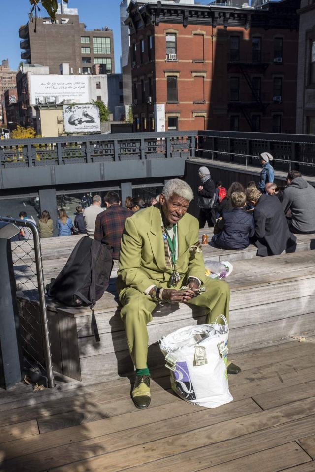 man in a green suit sitting on a wall on the high line in New York
