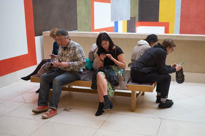 people on a bench at the Tate Britain in London - all on their phones - modern life