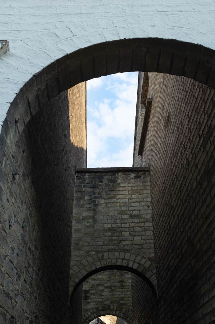 street scene showing a patch of blue sky above enclosed arches and walls in Cambridge